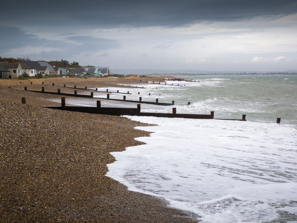 a stormy beach with a few houses in the background