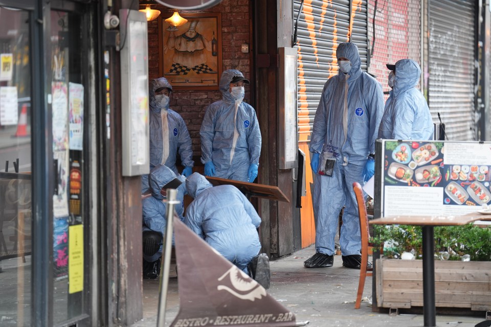 a group of men in protective suits are working outside a restaurant