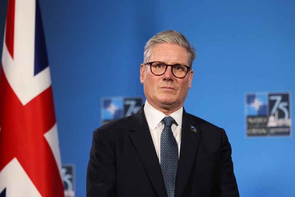 a man in a suit and tie stands in front of a british flag