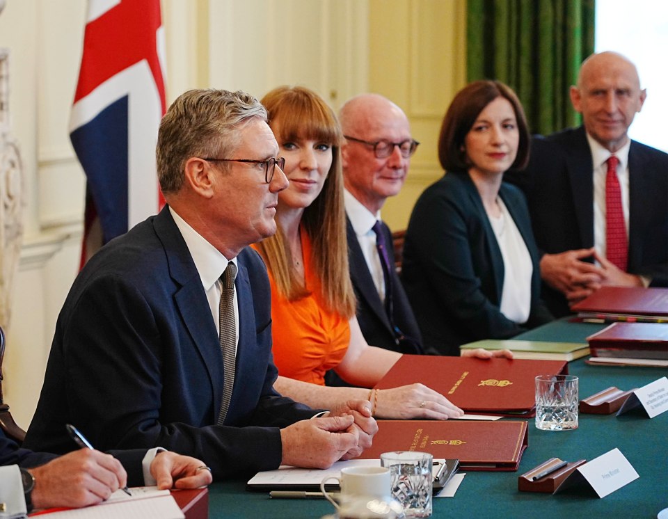 a group of people are sitting around a table with a folder that says ' foreign secretary ' on it