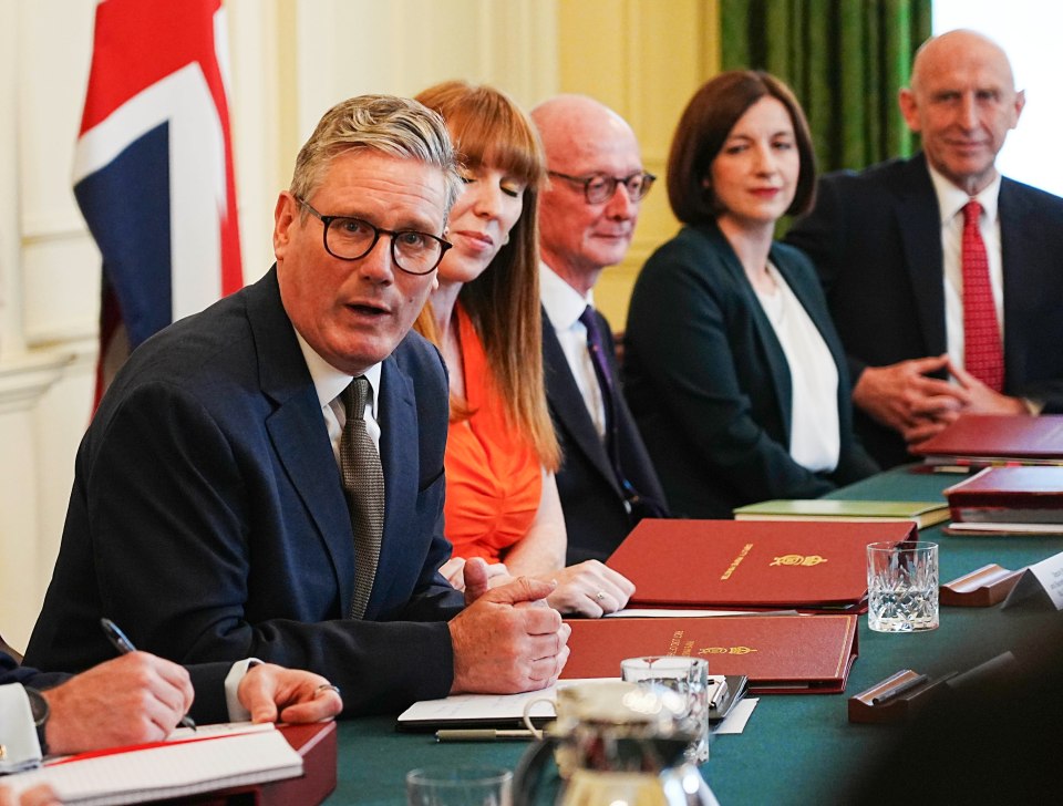 a man in a suit sits at a table with other people