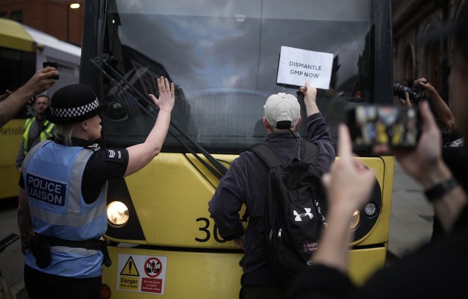 a man holds up a sign that says dismantle gmp now
