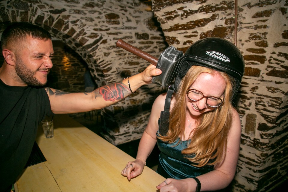 After downing a shot - and donning a helmet - she is hit on the head with a plastic hammer
