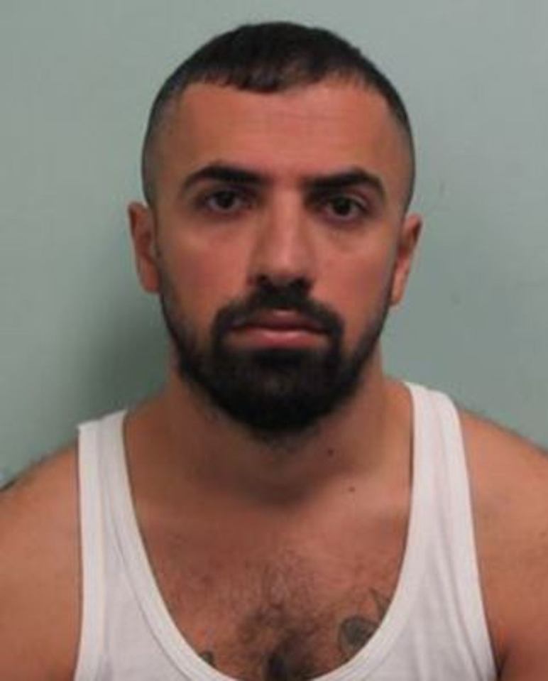 a man with a beard and a tattoo on his chest is wearing a white tank top .
