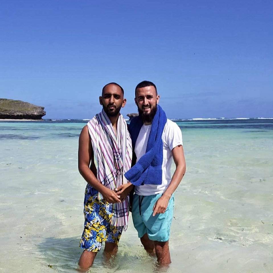 two men standing in the water with towels around their necks