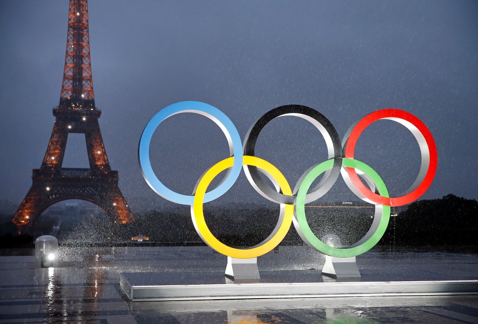 a statue of the olympic rings in front of the eiffel tower