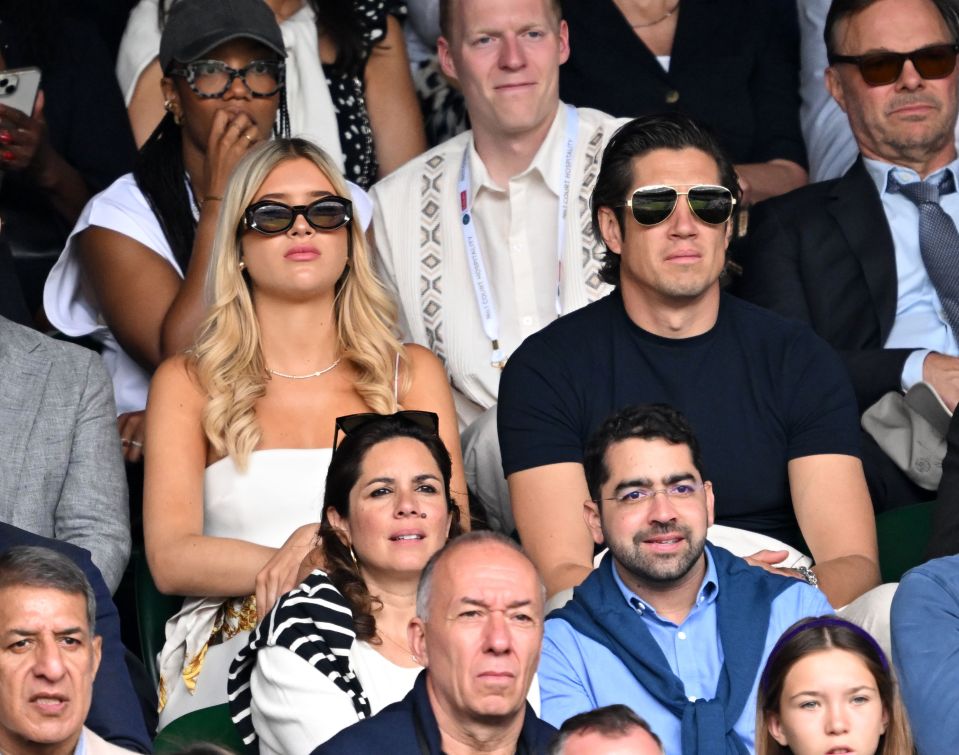 a woman wearing sunglasses sits in a crowd of people