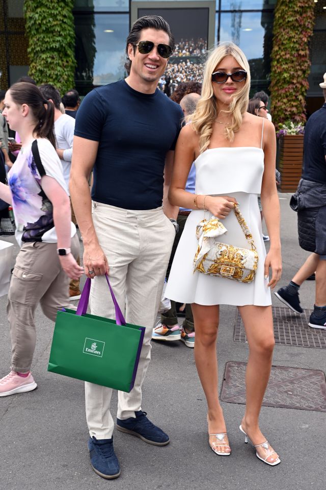 a man and woman standing next to each other with a green bag that says emirates on it