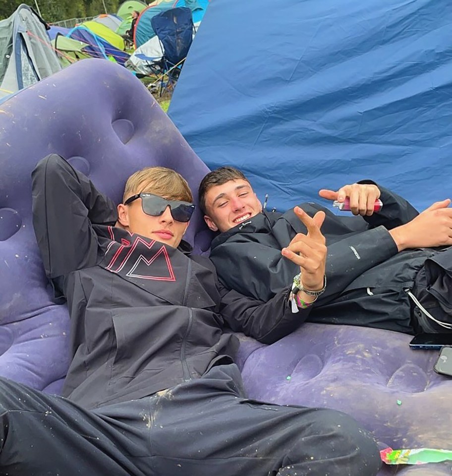Two friends relaxing on an inflatable air mattress at a festival.