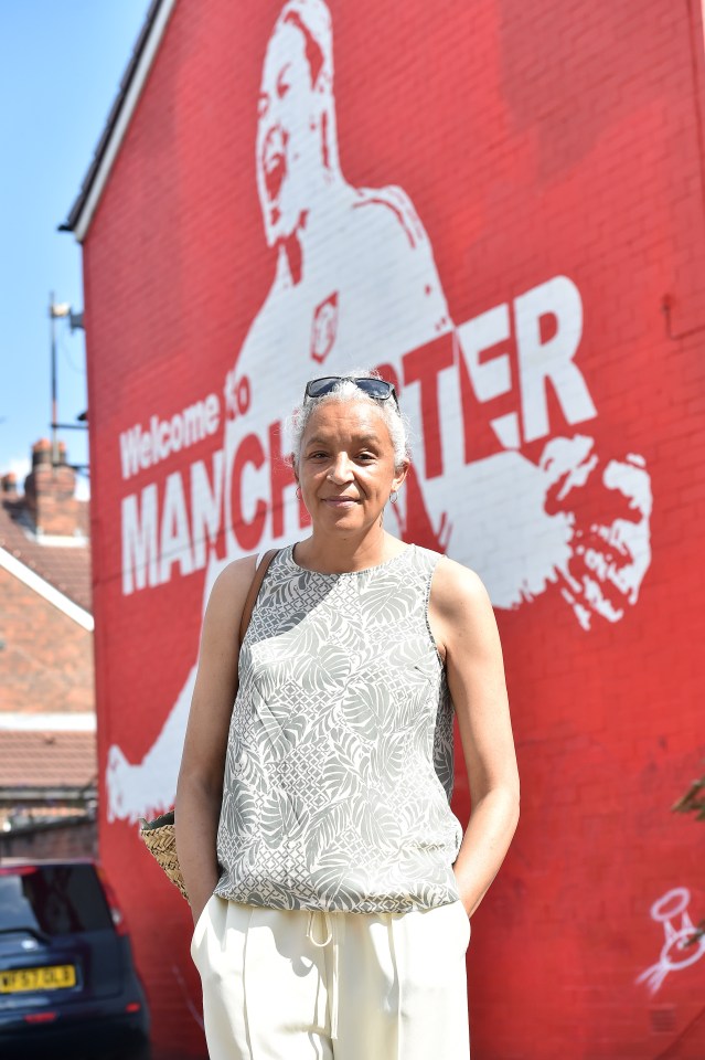 a woman wearing sunglasses and a tank top smiles for the camera