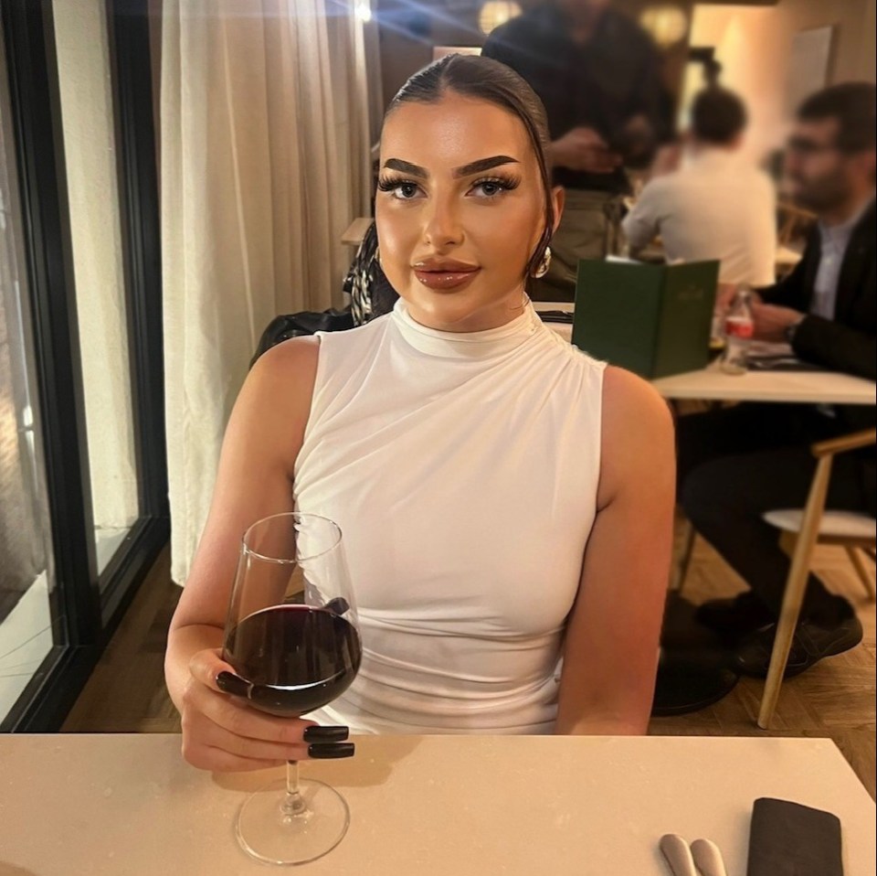 a woman sitting at a table holding a glass of wine