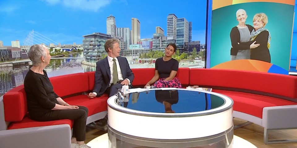 three people sit on a red couch in front of a screen that says 8:20