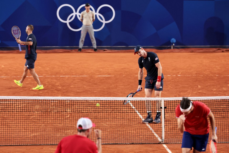 tennis players on a court with the olympic rings in the background