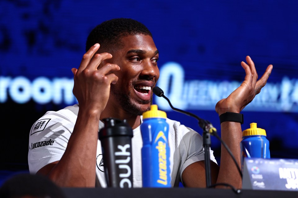 a man speaking into a microphone with a bottle of bulk in front of him
