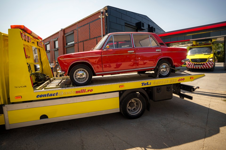 a red car is on the back of a yellow tow truck