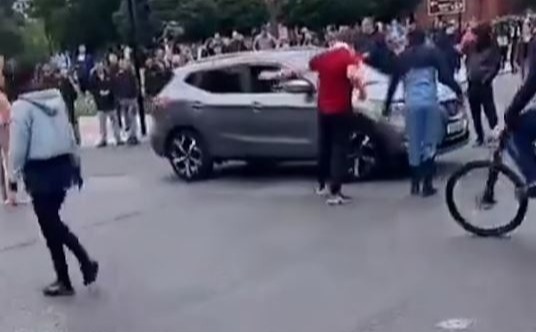 a group of people are standing in front of a car .