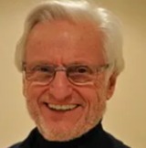 a man with glasses and a beard is smiling for the camera .