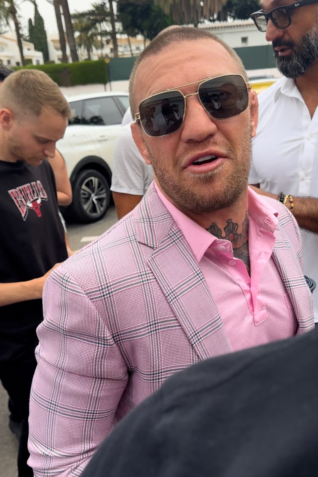 a man wearing sunglasses and a pink suit has a chicago bulls shirt on