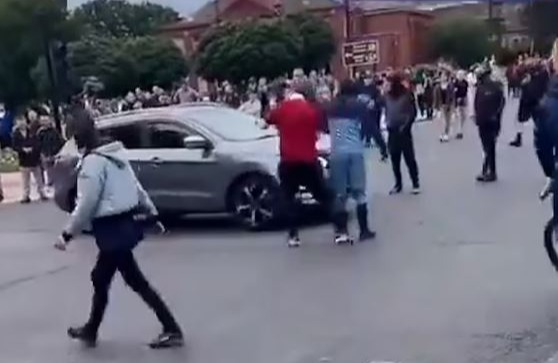 a group of people are standing in front of a car .
