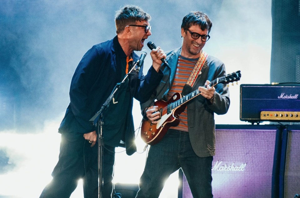 two men singing and playing guitar in front of a marshall amplifier