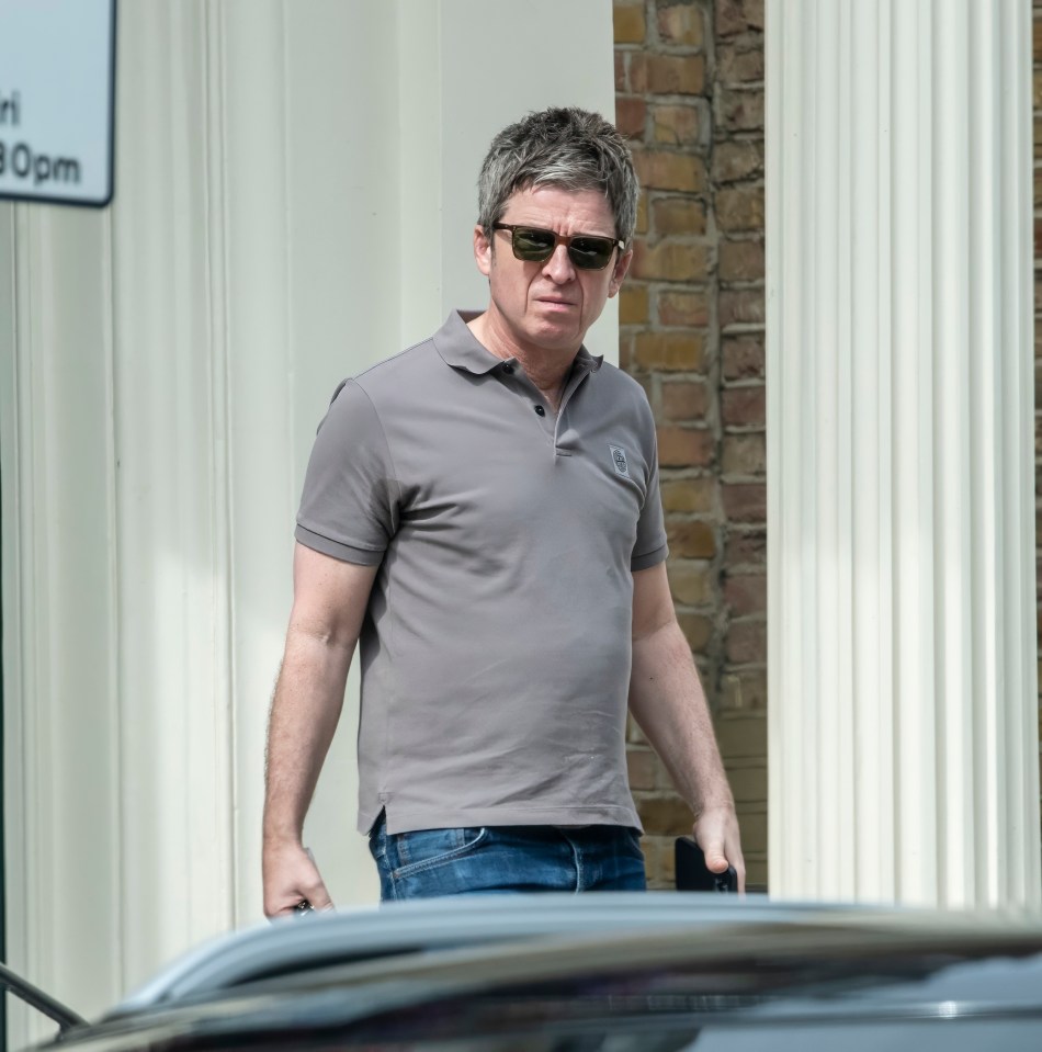 a man wearing sunglasses stands in front of a building with a sign that says ' parking ' on it