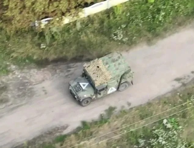 an aerial view of a military vehicle driving down a dirt road .