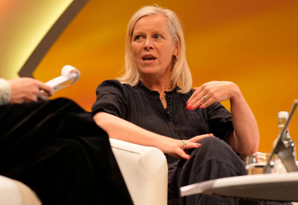 a woman sits in a chair talking to another woman with a yellow background