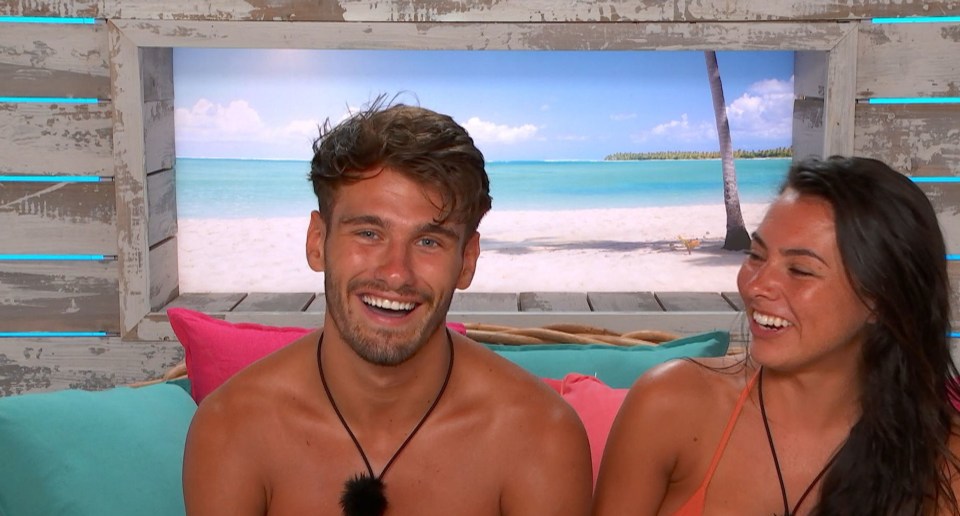 a man and a woman are smiling in front of a beach scene