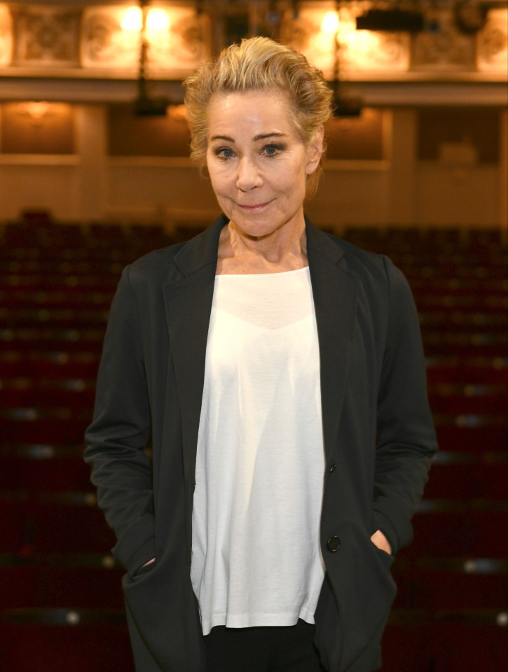 a woman with her hands in her pockets stands in an auditorium