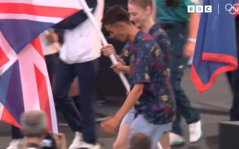 a man is holding a flag in front of a bbc logo