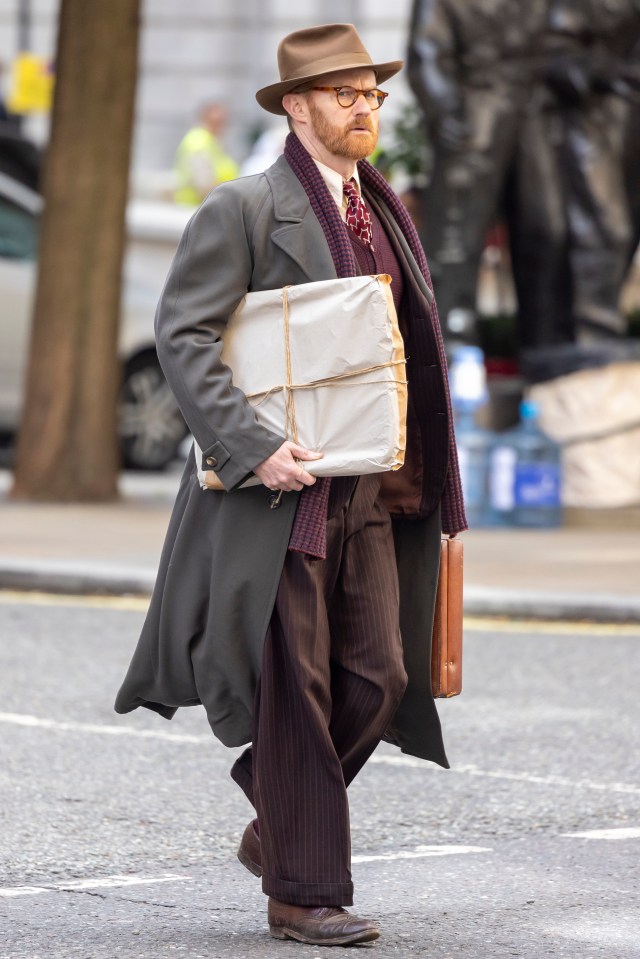 a man wearing a hat and glasses is walking down the street