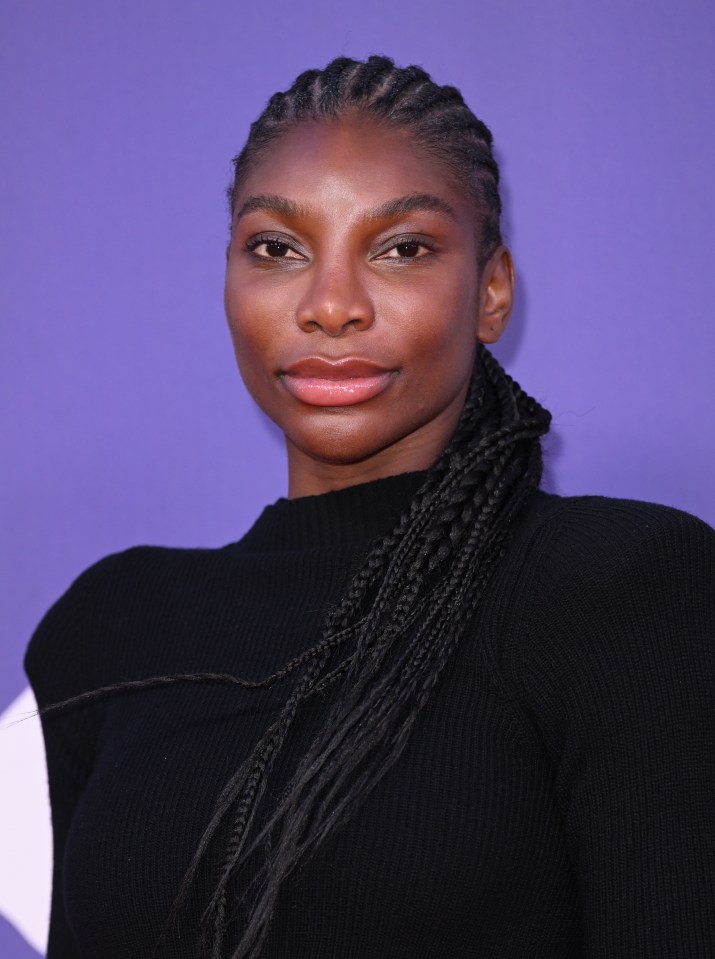 a woman with braids is wearing a black sweater