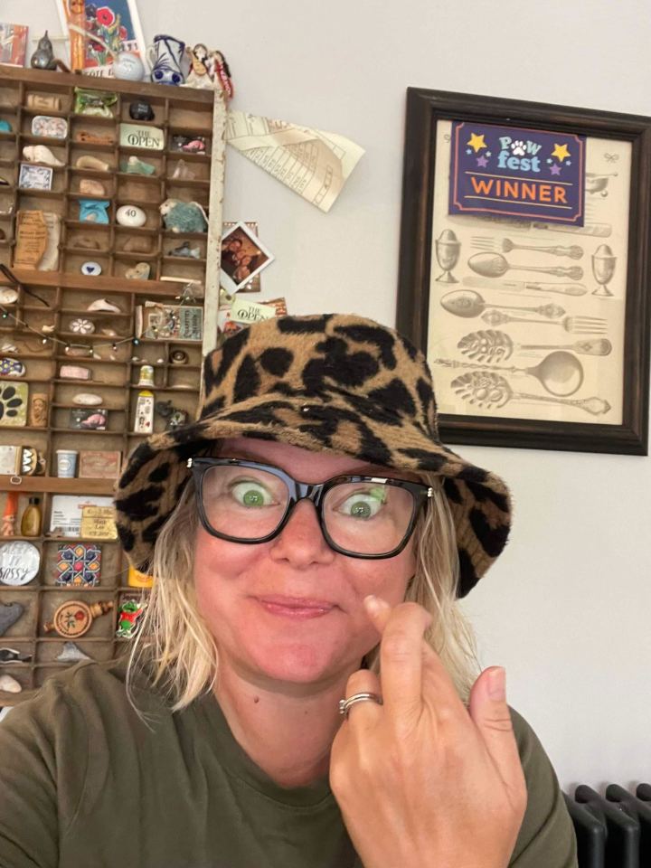a woman wearing a leopard print hat stands in front of a paw fest winner sign