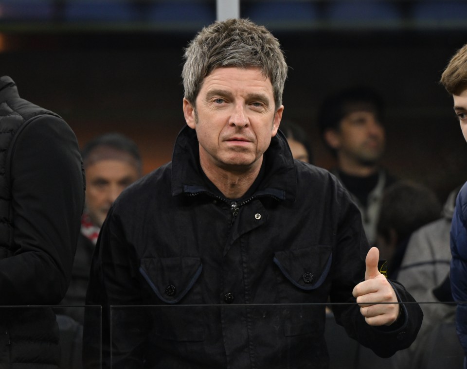 a man in a black jacket gives a thumbs up