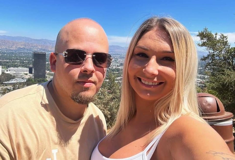 a man and a woman are posing for a picture with a city in the background