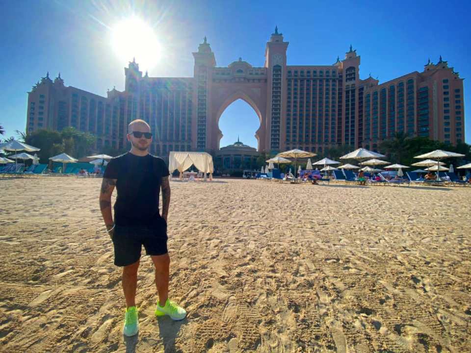 a man stands on a beach in front of a large building