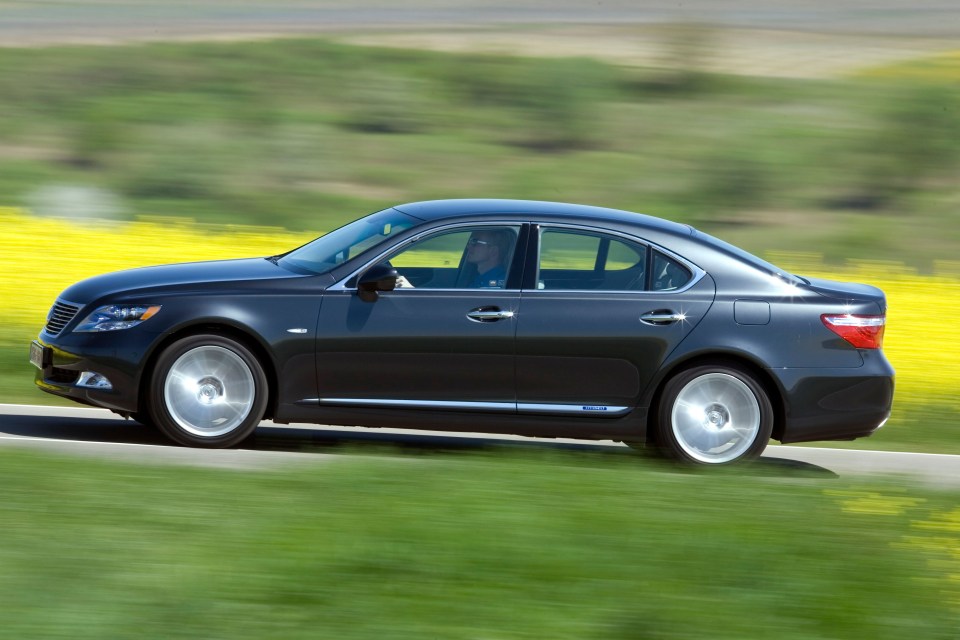 a black car is driving down a grassy road
