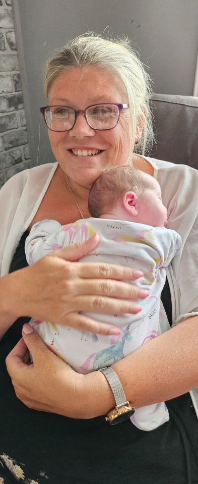 a woman wearing glasses is holding a baby in a unicorn outfit