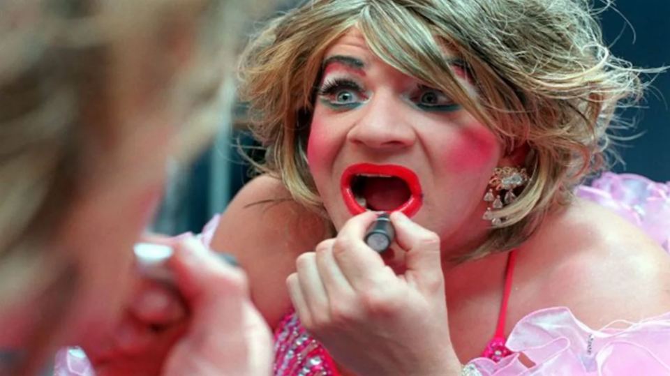 a woman in a pink dress is applying red lipstick