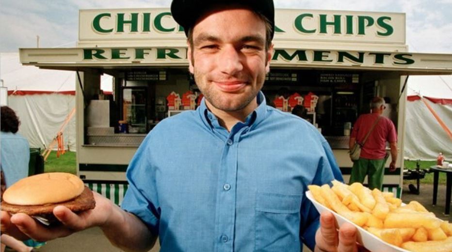 a man is holding a hamburger and french fries in front of a chick-fil-a
