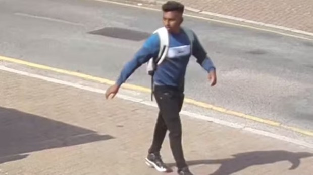 a man with a backpack is walking down the street .