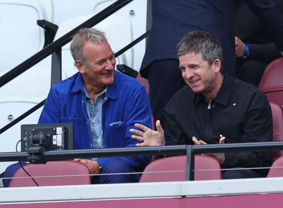 a man in a blue jacket sits next to a man in a black shirt