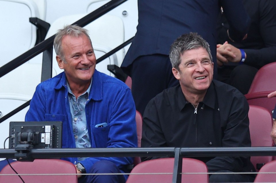 a man in a blue jacket sits next to another man in a black shirt