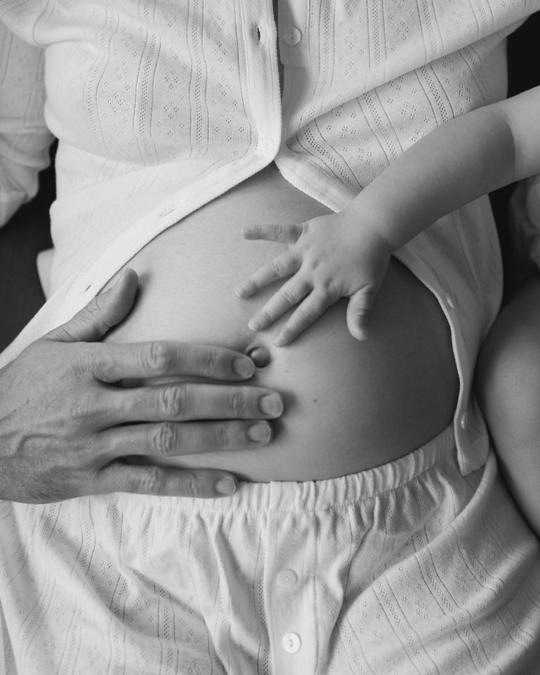 a child 's hand rests on a pregnant woman 's belly