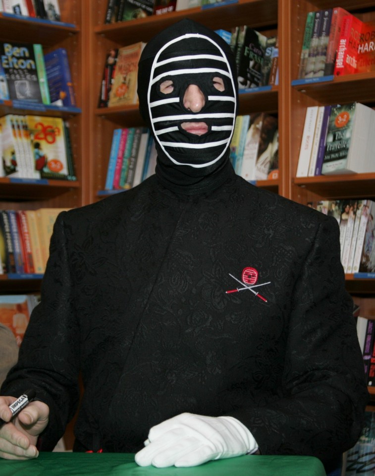 a man in a mask is signing a book in a bookstore