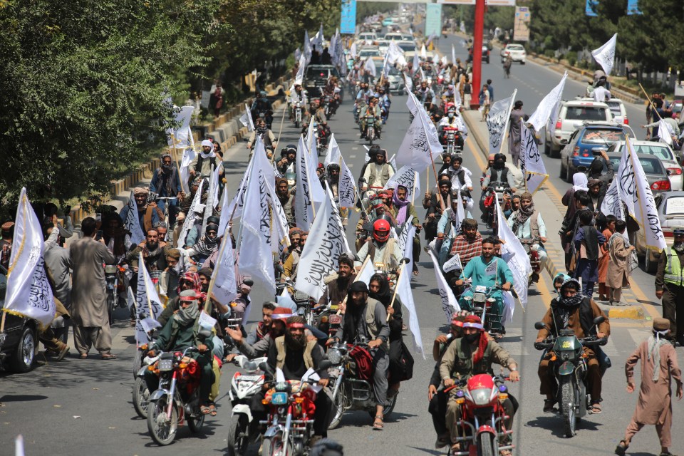 a group of people are riding motorcycles down a street while holding flags with arabic writing on them