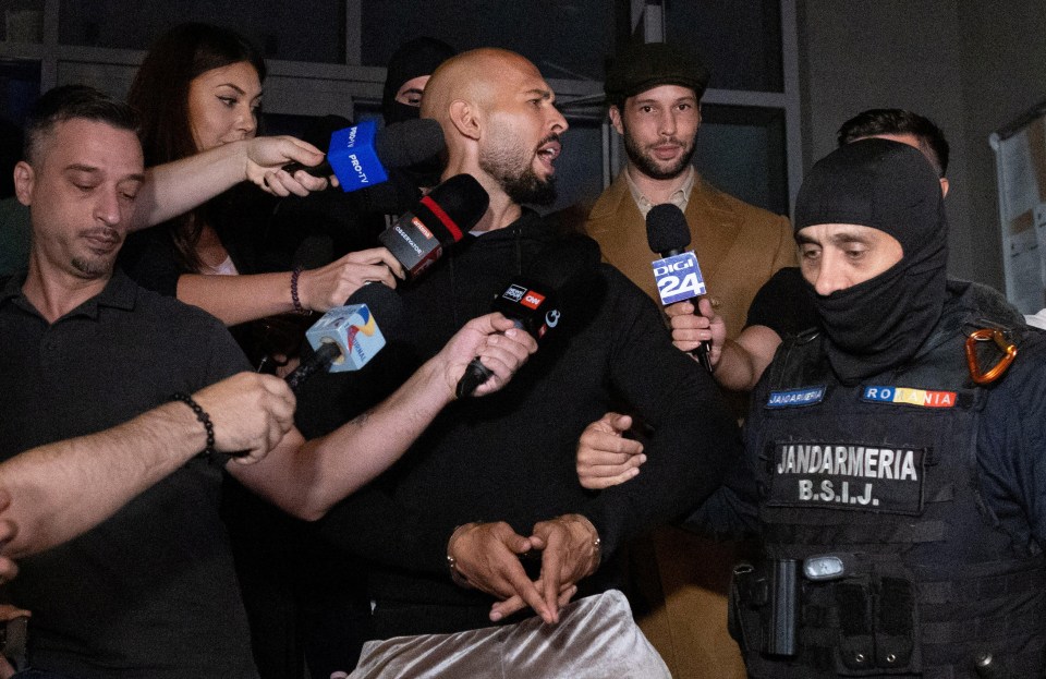 a man in a jandarmeria uniform is surrounded by people holding microphones