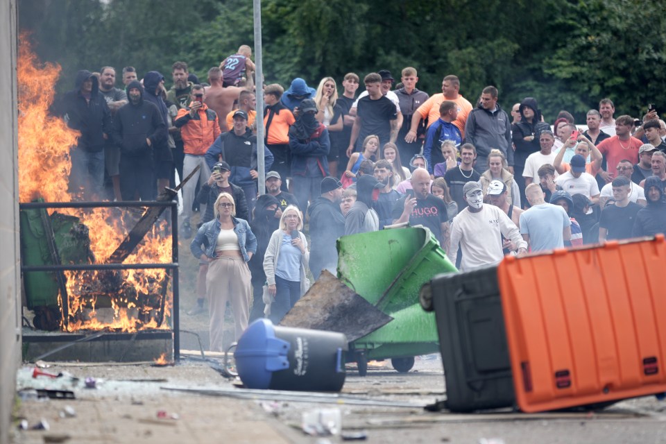 a man wearing a hugo shirt stands in front of a fire