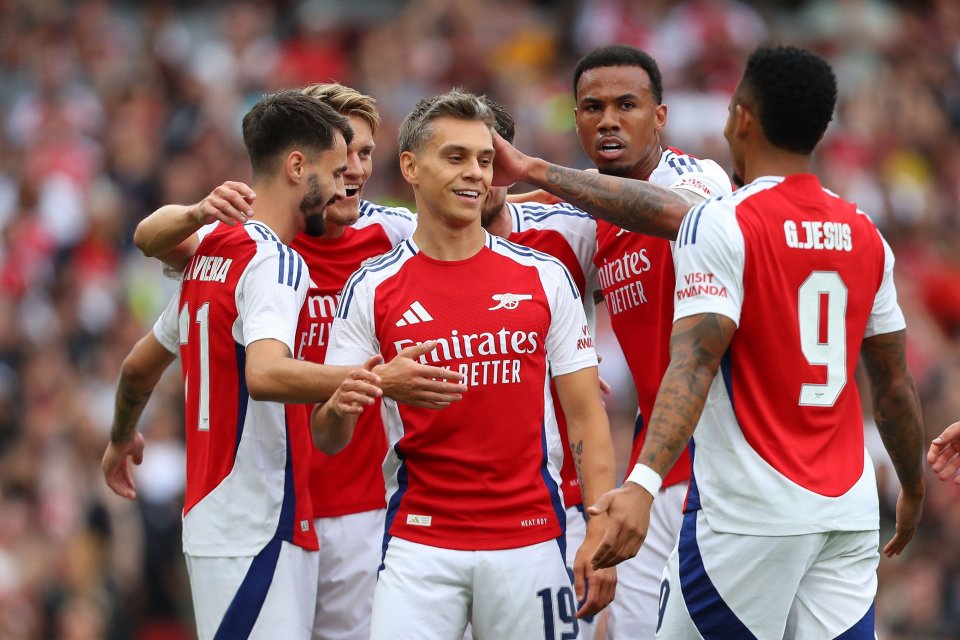 a group of soccer players with one wearing a red emirates better jersey