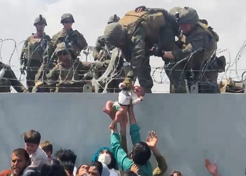 a soldier holds a baby over a crowd of people